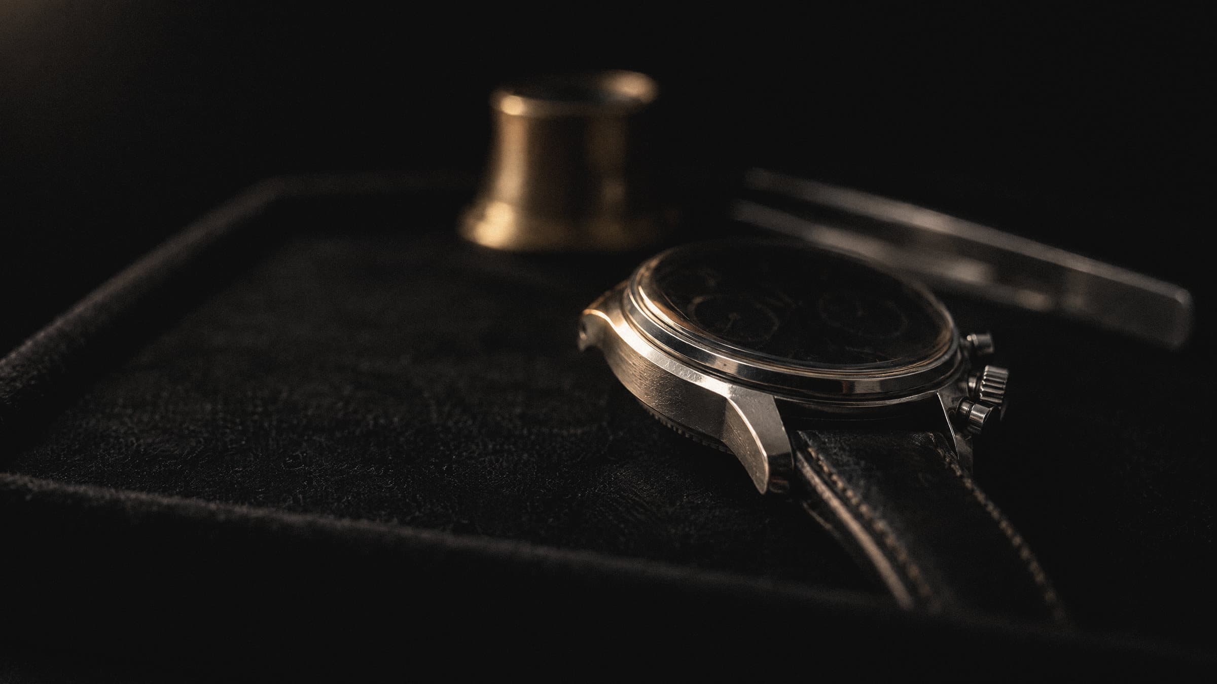 Vintage chronograph on a velvet tray with a loupe and tweezers