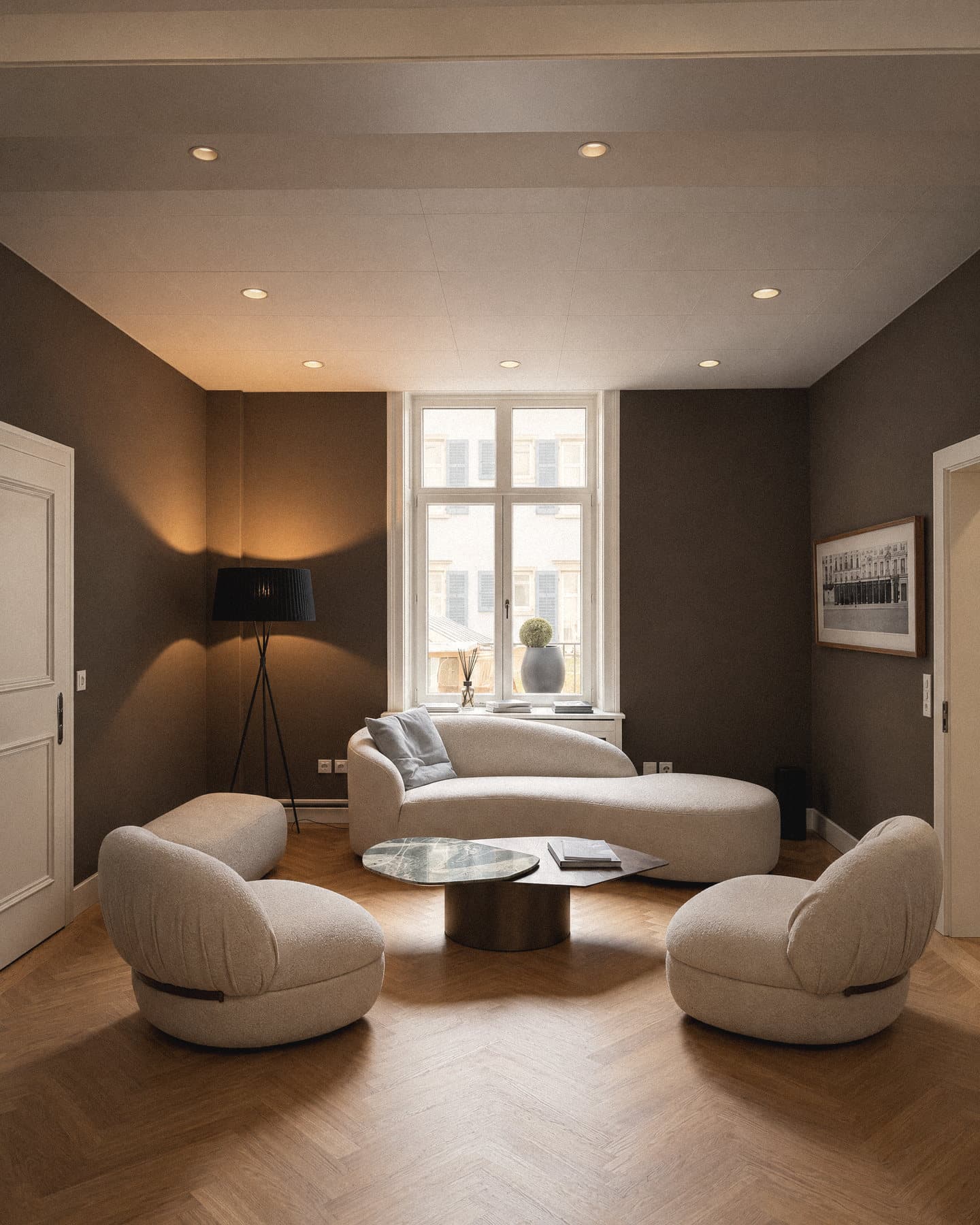 The lounge at Freigutstrasse 20: herringbone parquet, a curved sofa and two armchairs at the bay window