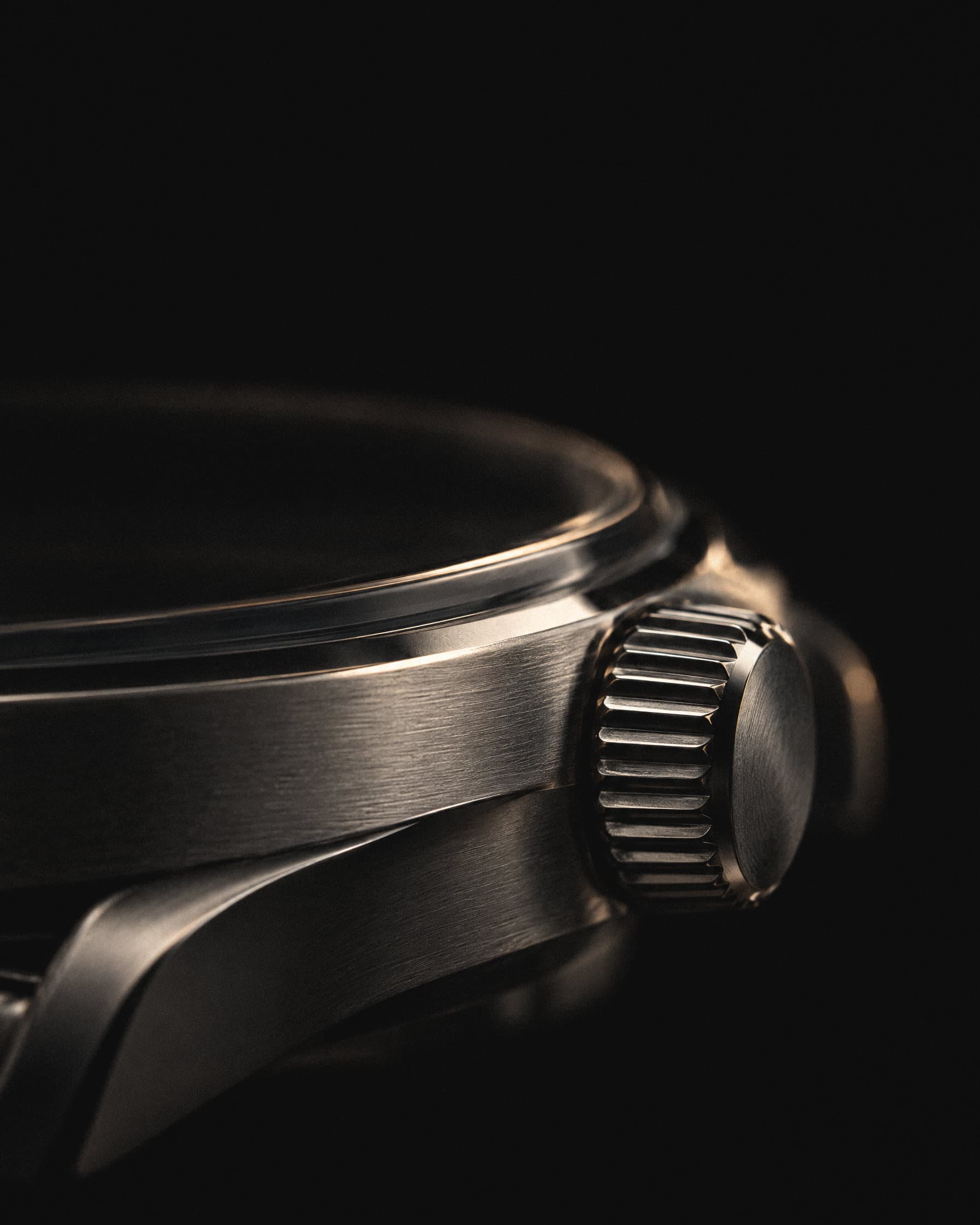 Steel watch case and fluted crown, close-up on black